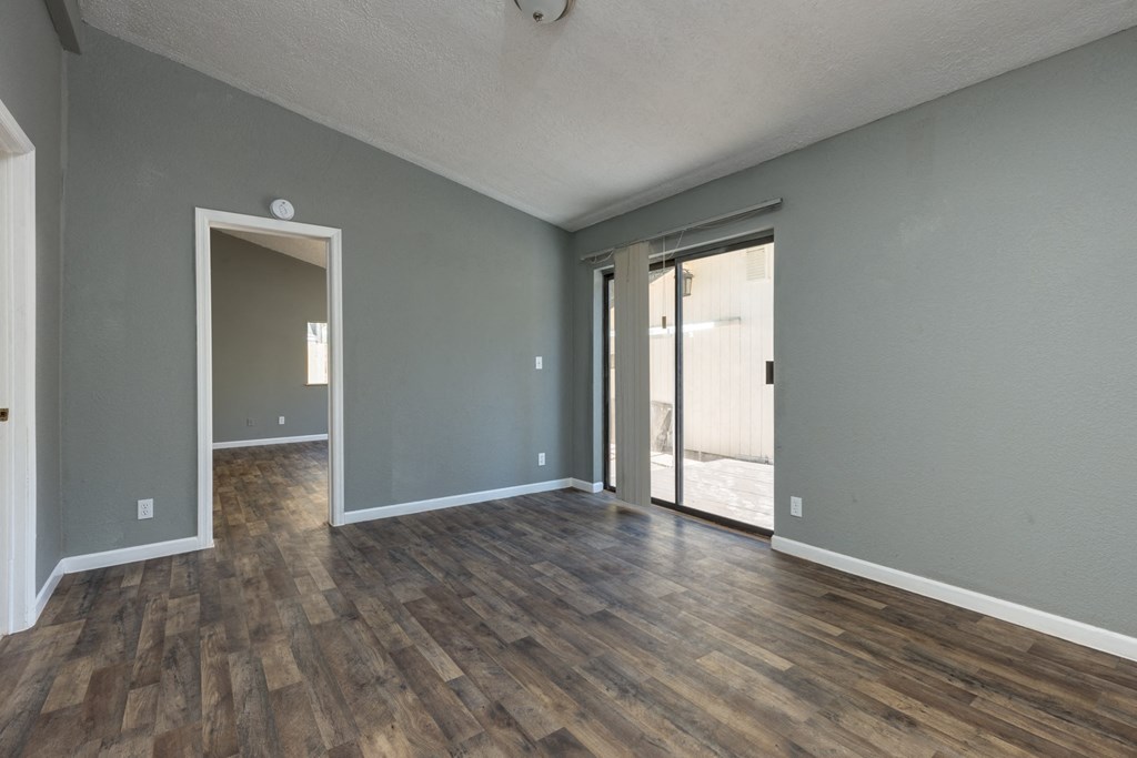an empty living room with grey walls and wood floors