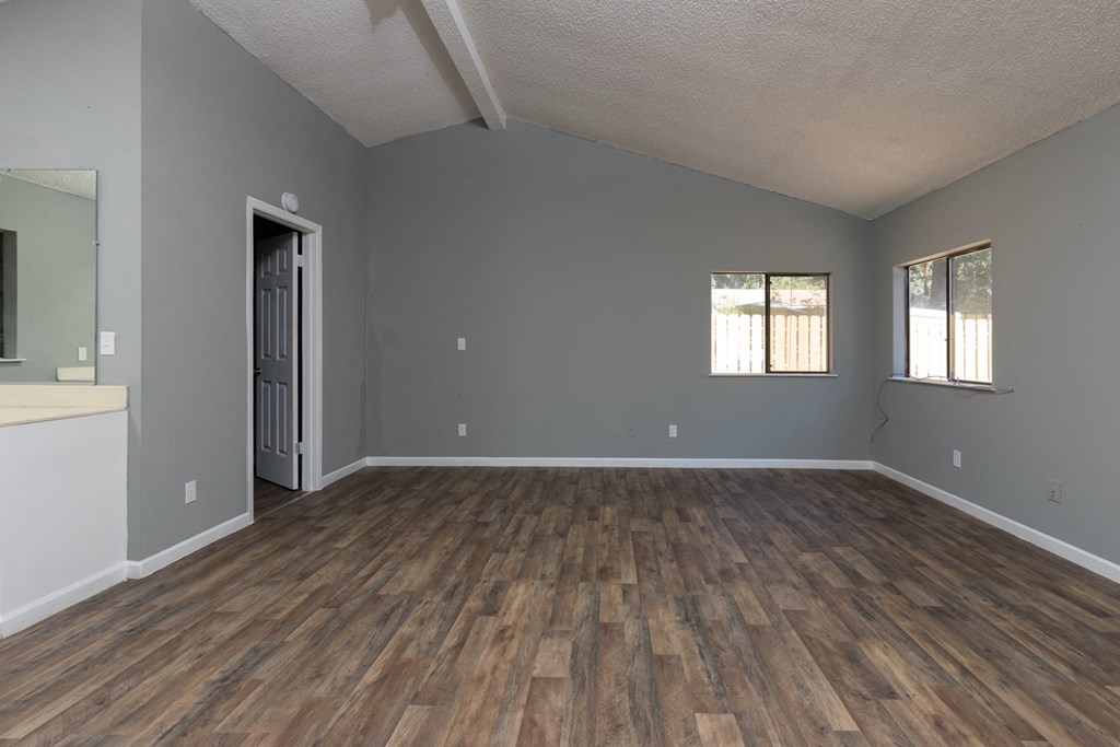 an empty living room with wood floors and grey walls
