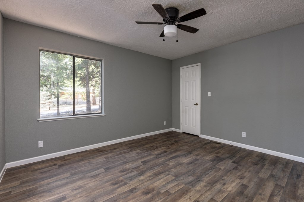an empty living room with a window and a ceiling fan