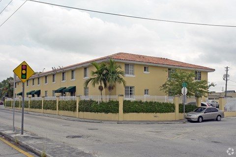 A yellow building with a red roof and a car parked in front.