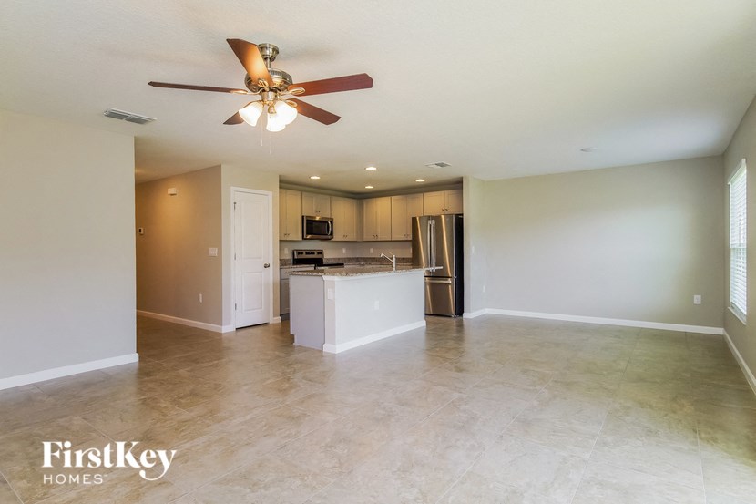 A spacious kitchen and living room with a ceiling fan.