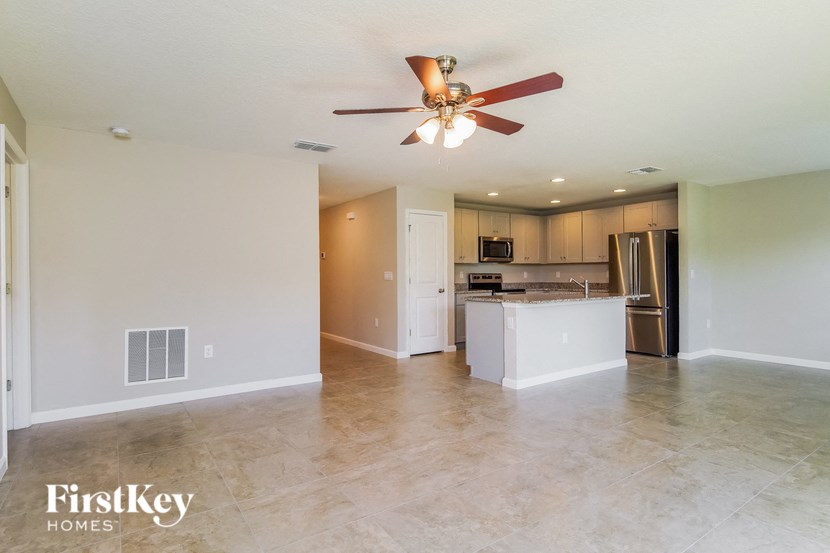 A spacious kitchen and living room with a ceiling fan.