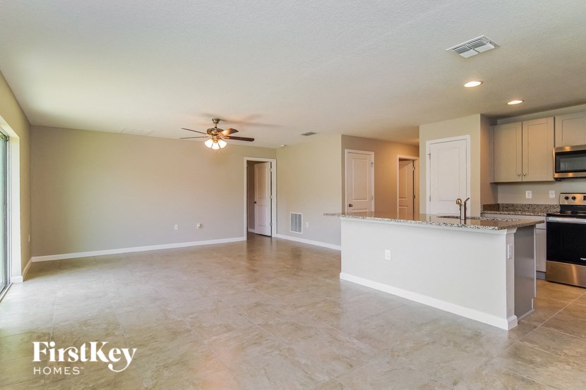 A spacious kitchen and living room with a ceiling fan and lighting.