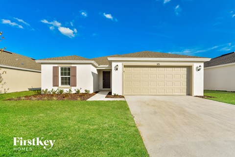 a beige house with a garage door and a lawn