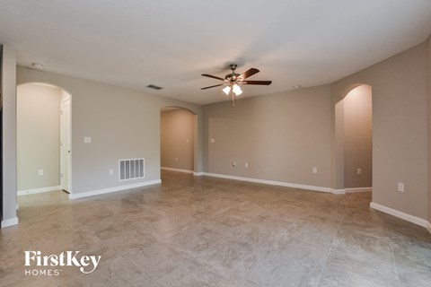 the spacious living room with tile flooring and ceiling fan