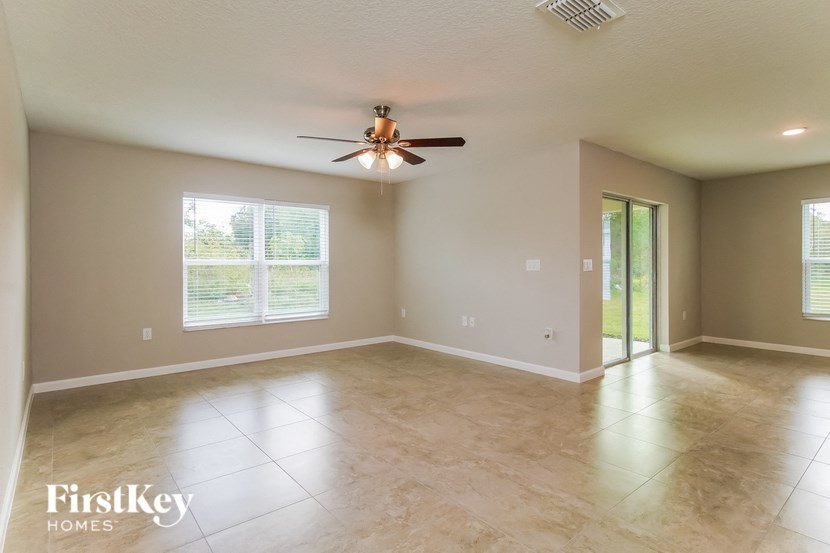an empty living room with a ceiling fan and a window