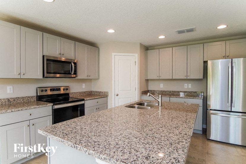a white kitchen with granite counter tops and stainless steel appliances