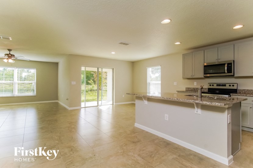 an open kitchen and living room with a marble counter top