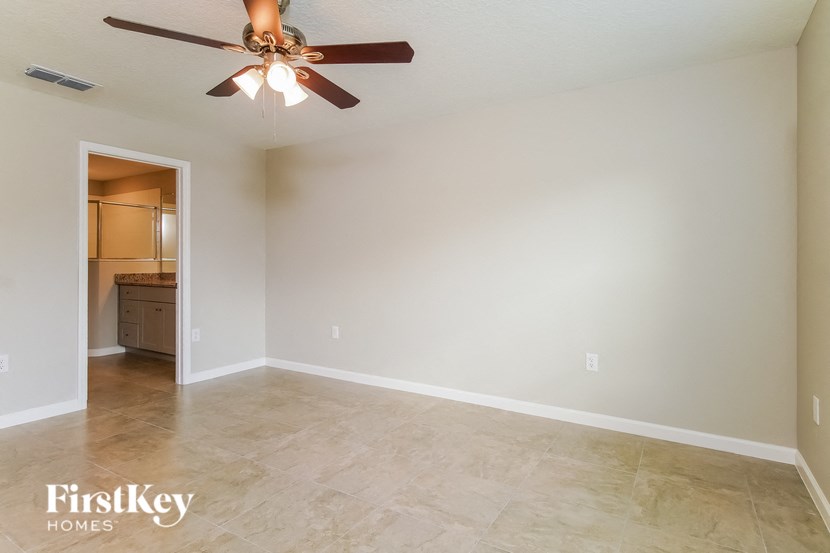 a empty living room with a ceiling fan and tile floor