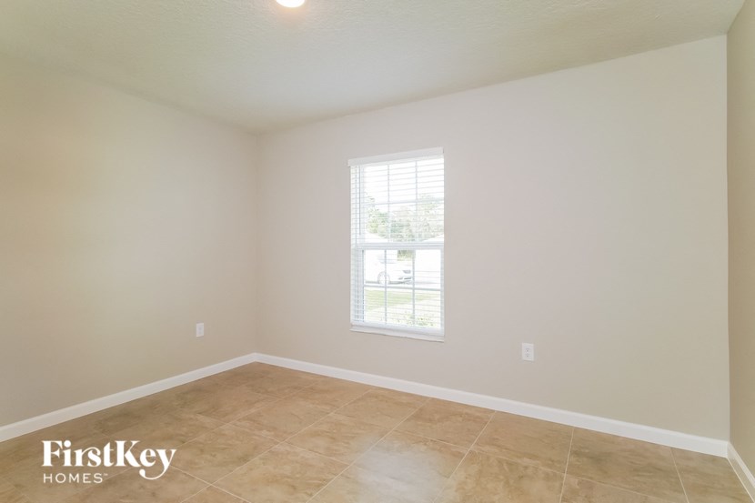 the living room of an empty house with a window and tiled floors