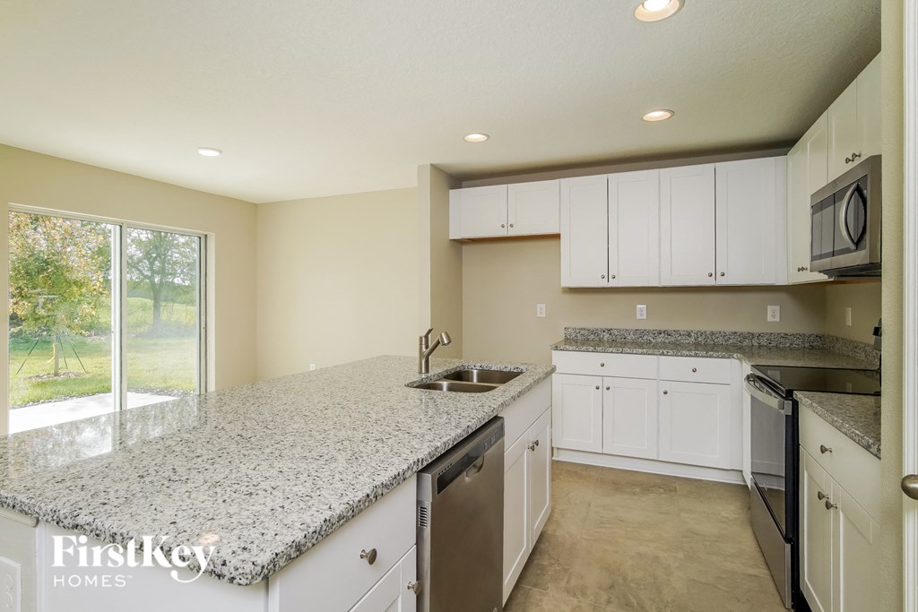 a kitchen with white cabinets and granite counter tops and a sink