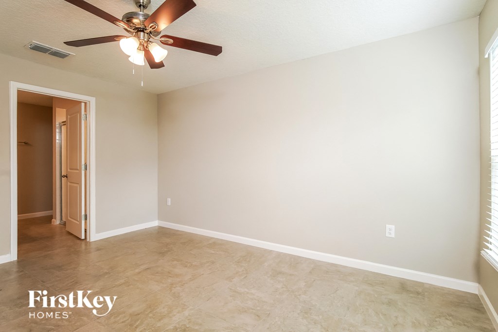 a empty living room with a ceiling fan and a door to a closet
