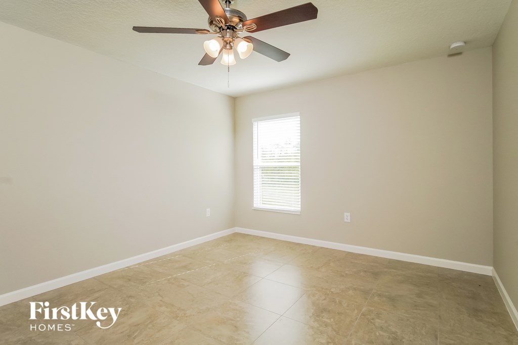 a empty room with a ceiling fan and tile floor