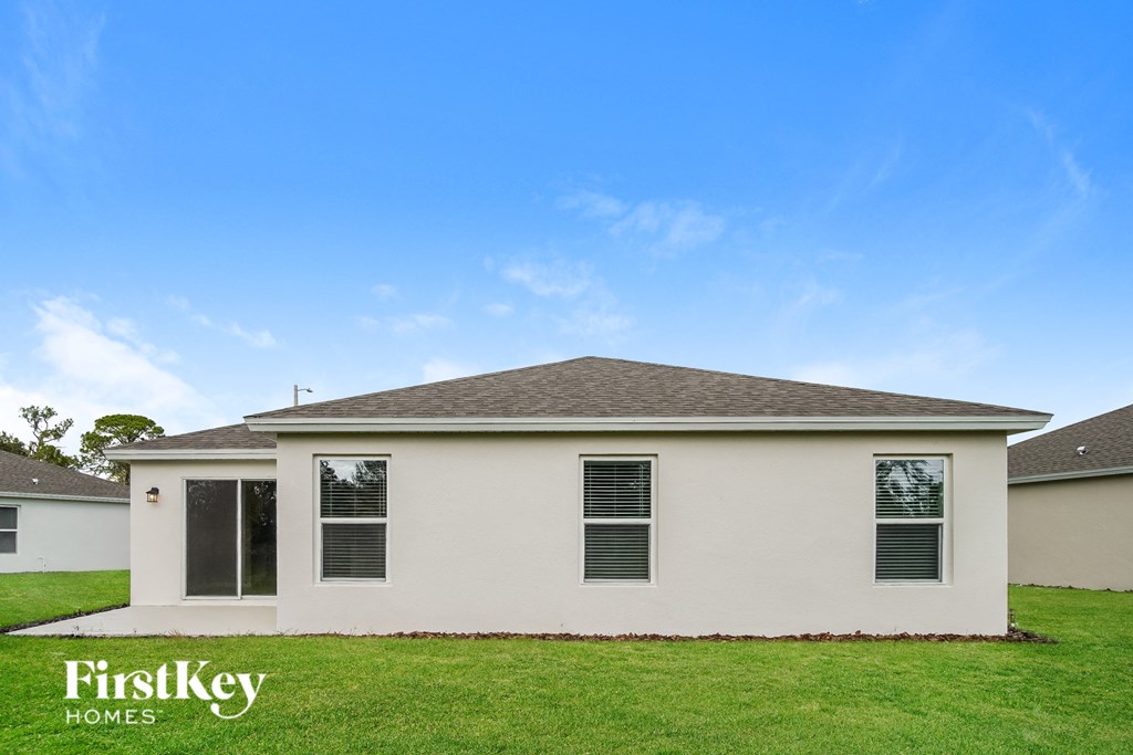 a small white house with a green lawn and a blue sky