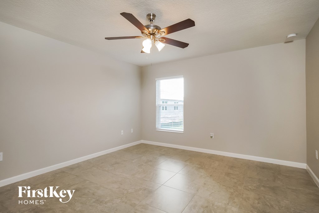 a empty living room with a ceiling fan and a window