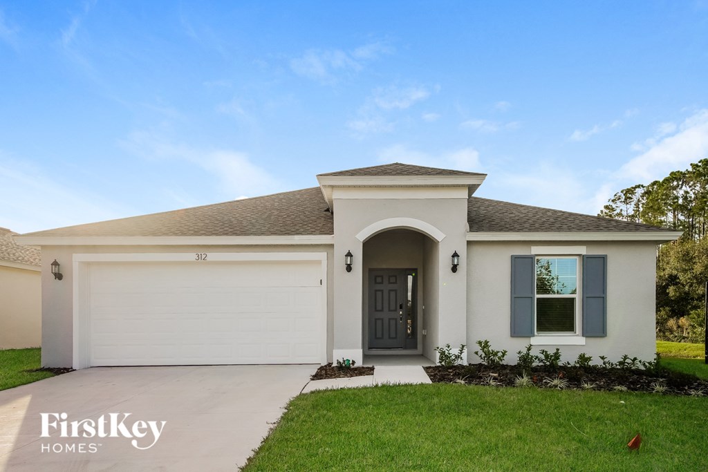 the exterior of a white house with a driveway and grass