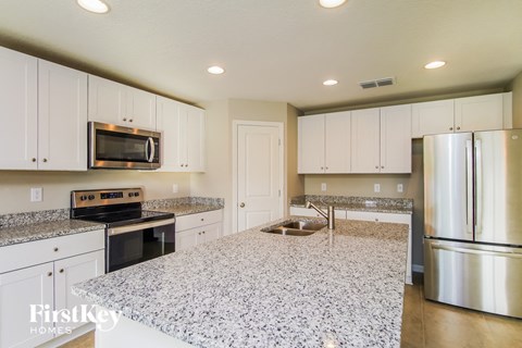 a white kitchen with granite counter tops and stainless steel appliances