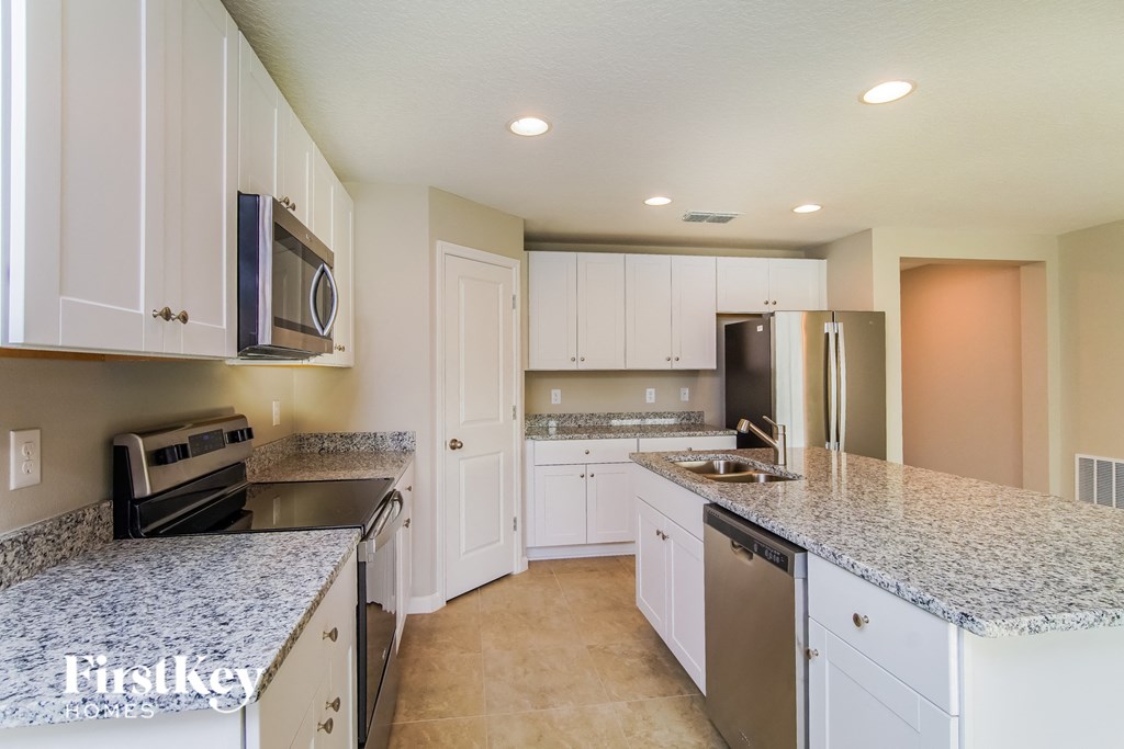 a white kitchen with granite counter tops and stainless steel appliances