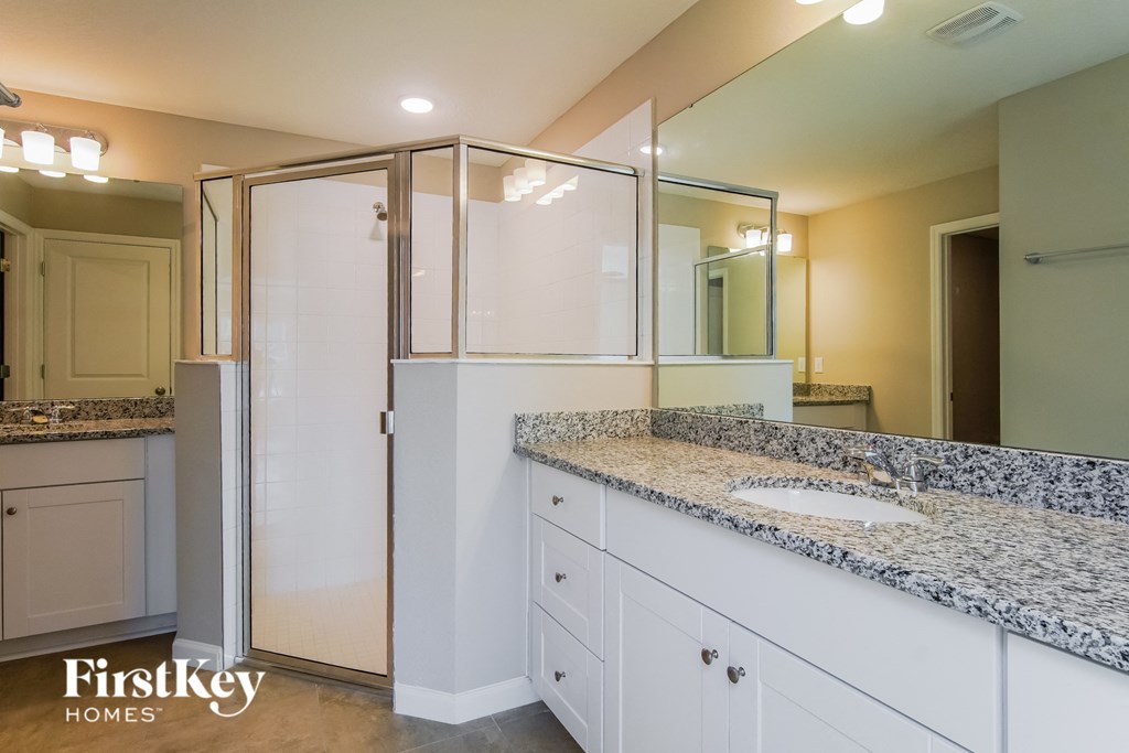 a bathroom with white cabinets and a sink and a shower
