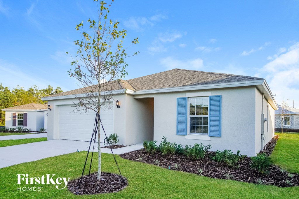 a white house with blue shutters and a tree in the front yard