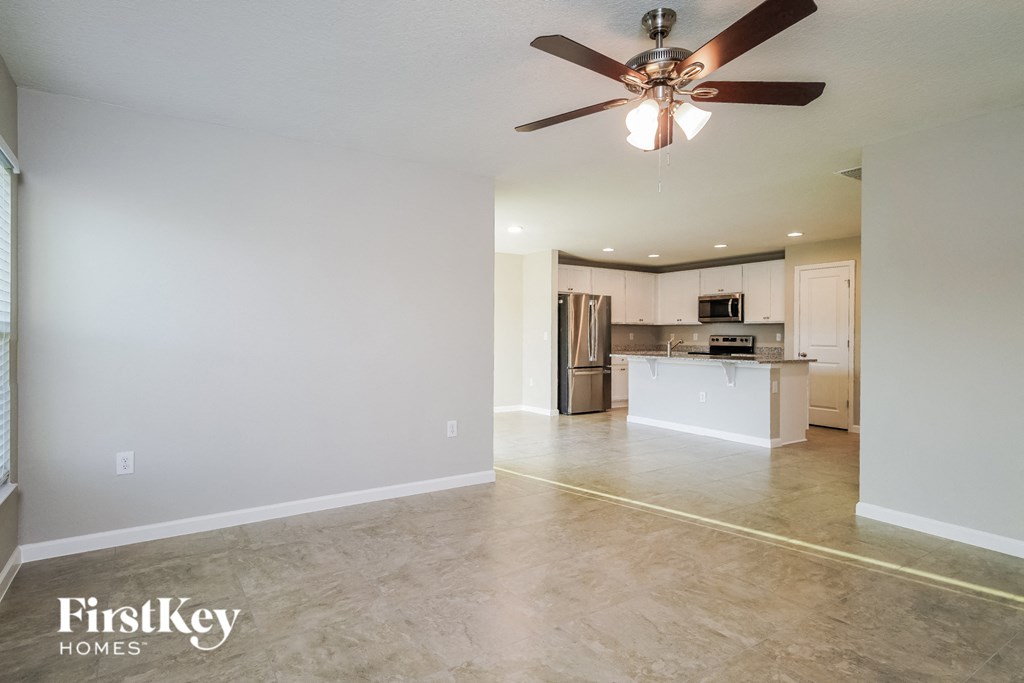 an empty living room and kitchen with a ceiling fan