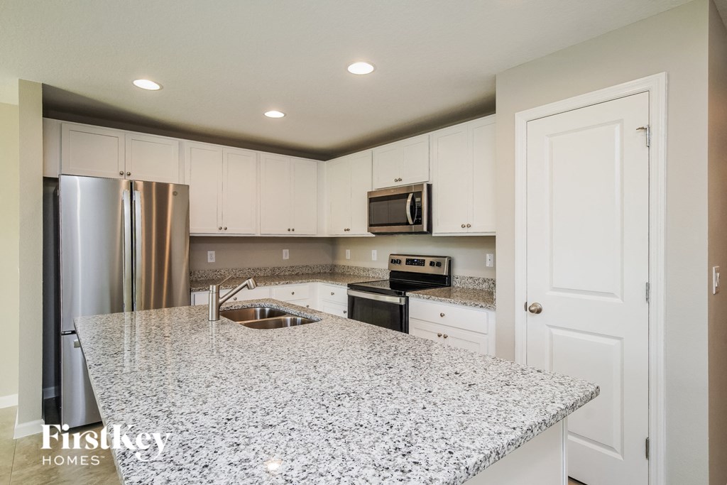 a kitchen with white cabinets and a granite counter top