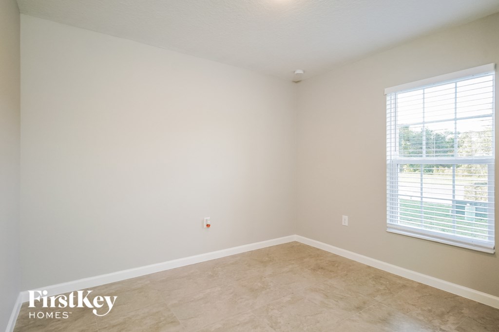 a bedroom with a large window and a tiled floor