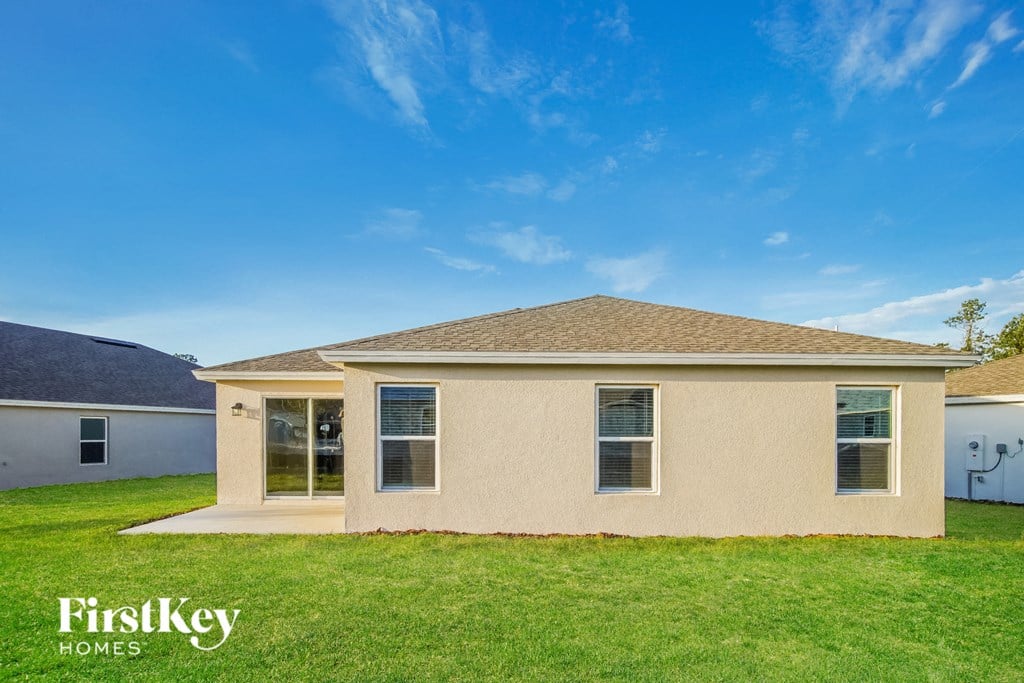 a beige house with a lawn and a blue sky