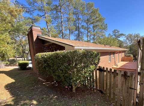 a house with a fence and a hedge in front of it