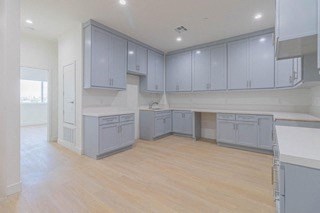 an empty kitchen with blue cabinets and a wooden floor
