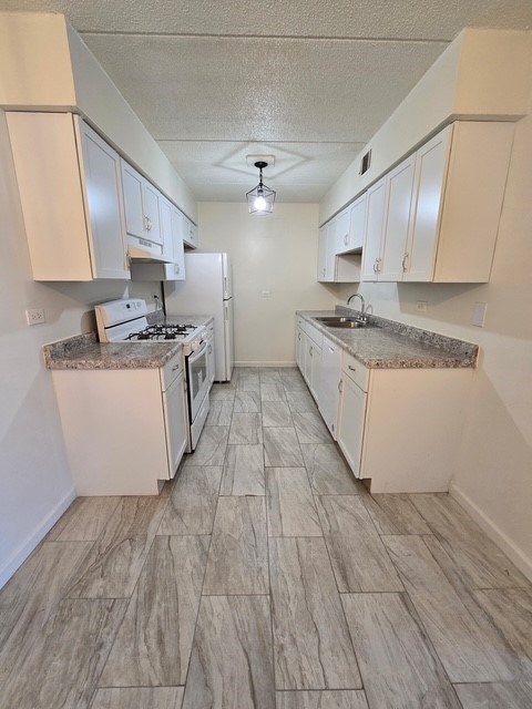 A kitchen with white cabinets and a tile floor.