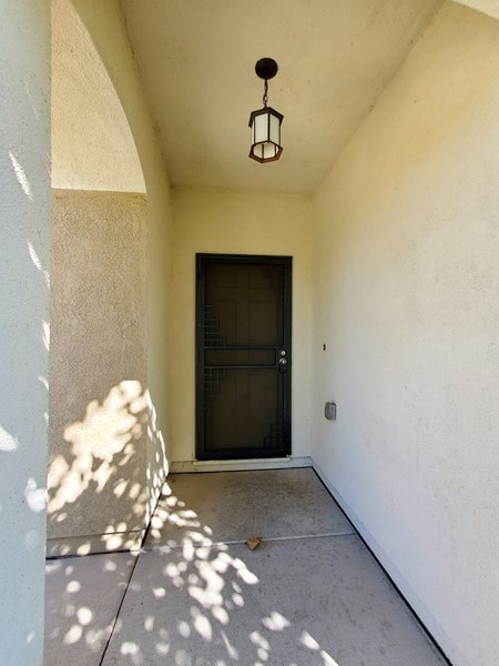 A hallway with a black door and a hanging light fixture.