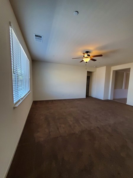 A room with a ceiling fan and a window with blinds.