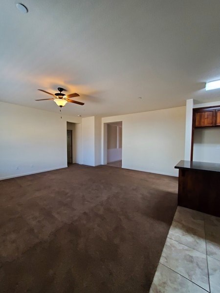 A room with a ceiling fan and brown carpet.
