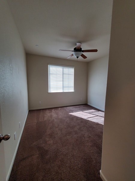 A room with a ceiling fan and a window with blinds.