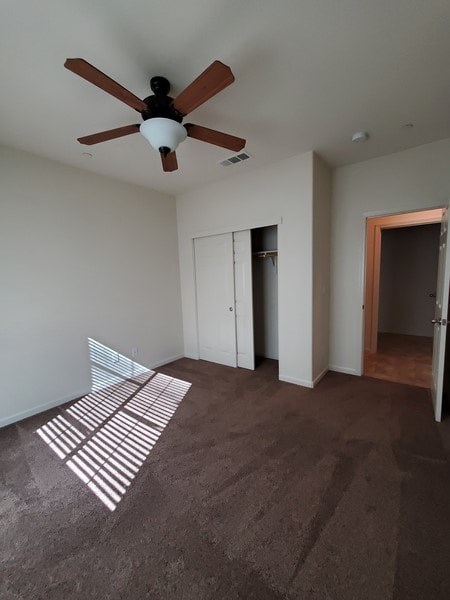 A room with a ceiling fan and carpeted floor.