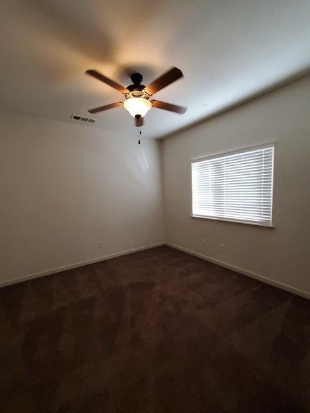 A room with a ceiling fan and a window with blinds.