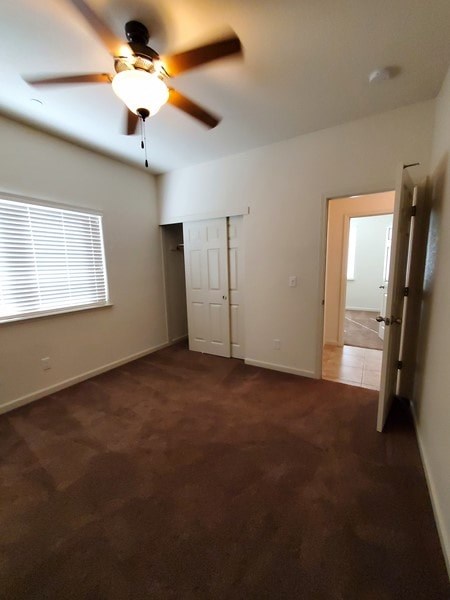 A room with a ceiling fan and carpeted floor.