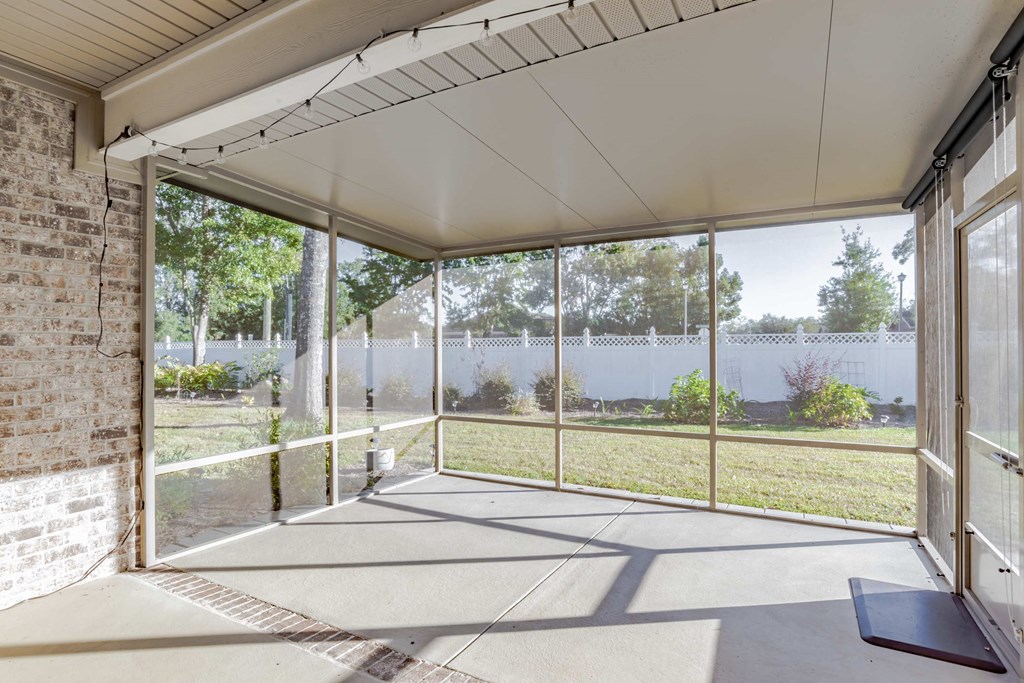 A sunny day in a room with a glass wall and a brick wall.