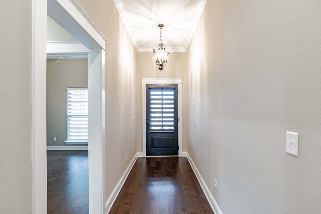 A hallway with a chandelier and a black door.