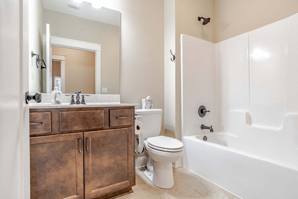 A white bathroom with a wooden vanity and a white toilet.