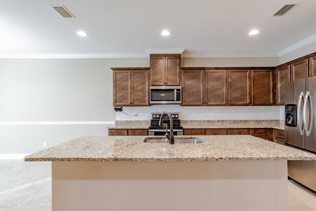 A kitchen with a granite countertop and wooden cabinets.