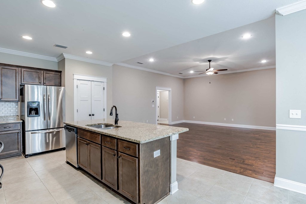 A kitchen with a refrigerator, sink, and cabinets.