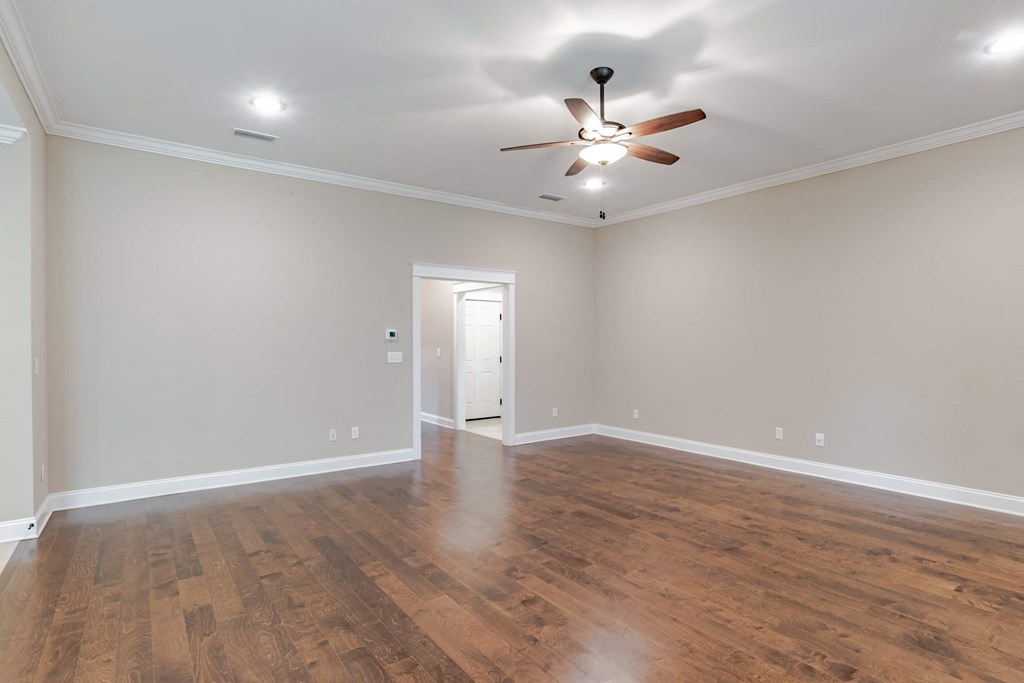 A room with a ceiling fan and wooden flooring.