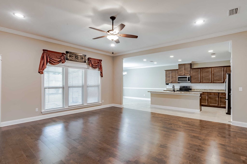A spacious room with a ceiling fan and wooden flooring.