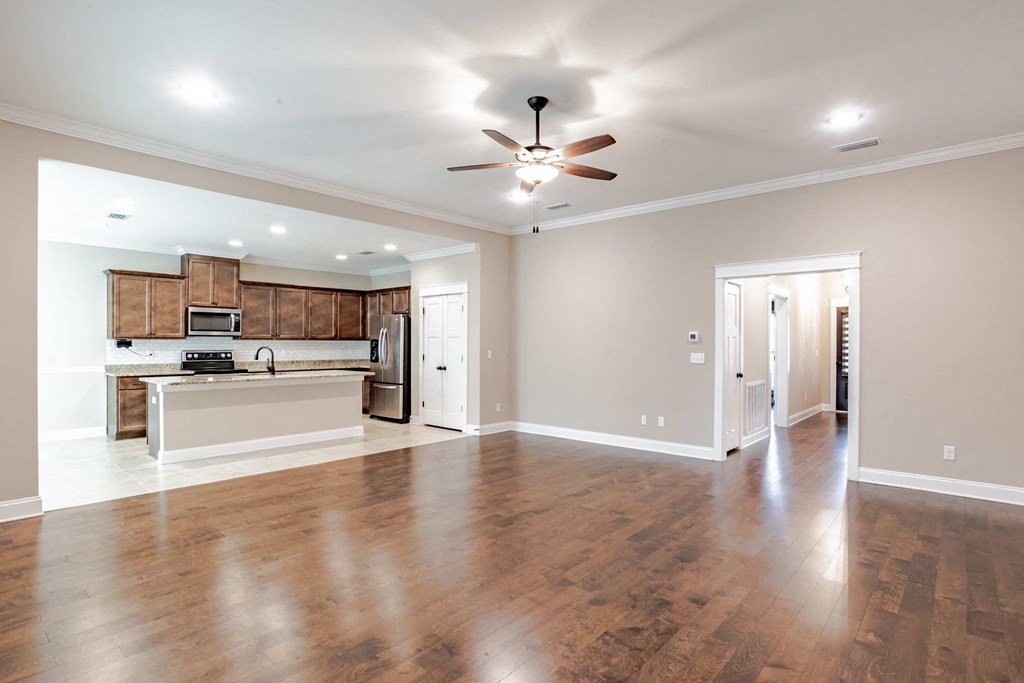 A spacious room with wooden floors and a ceiling fan.