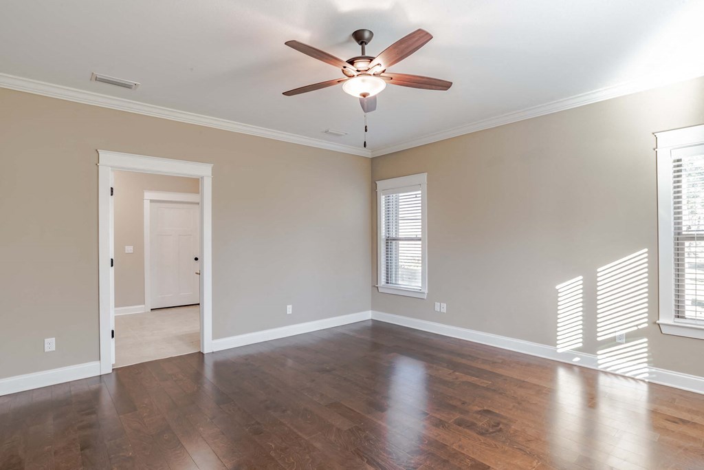 A room with a ceiling fan and wooden floors.