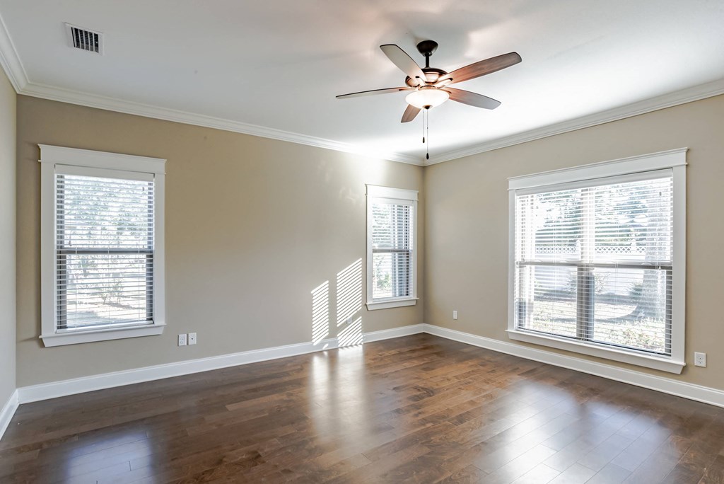 A room with a ceiling fan and wooden floors.