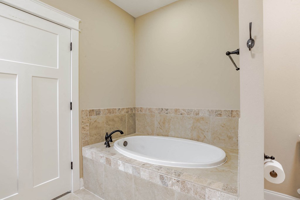 A white bathroom with a tub and a door.