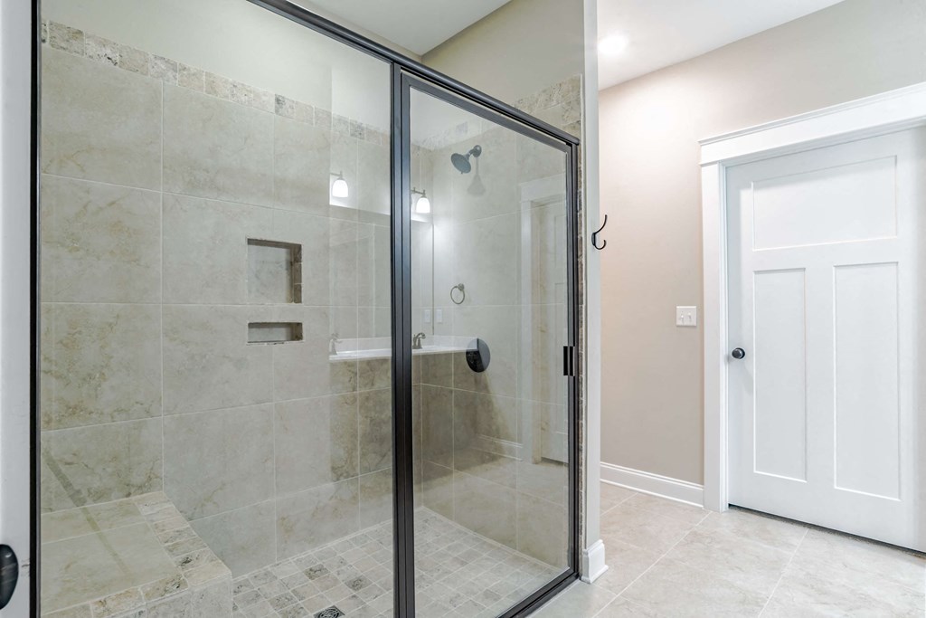 A bathroom with a walk-in shower and a white door.